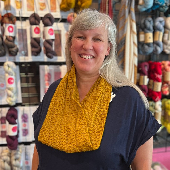 Woman wearing a yellow knitted scarf in a yarn store