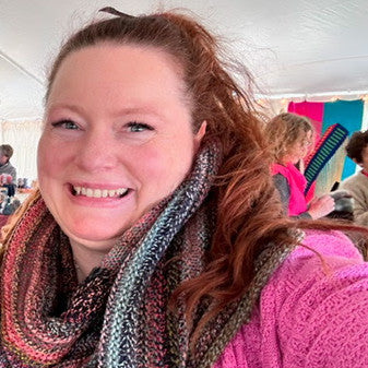 Woman wearing a colorful scarf and pink sweater with blurred background