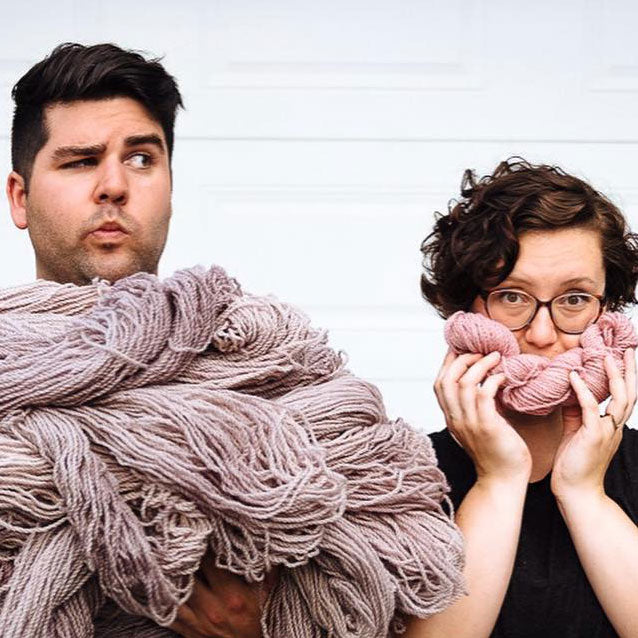 Julie and Jean-François of Julie Asselin Yarns holding armfuls of pink yarn