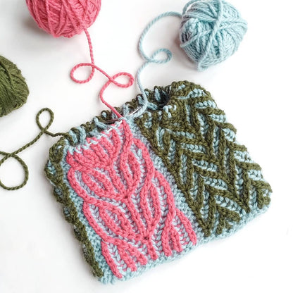 Colour-blocked brioche swatch in pink, green and pale blue with yarn balls